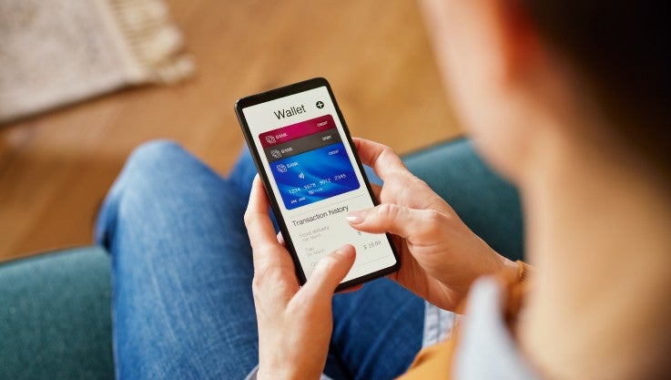 A person holds their phone. On the screen are three virtual cards.